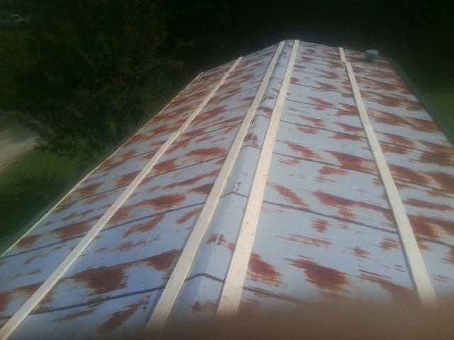 Rusted metal roof panels with new wood purlins before replacement in Lenox