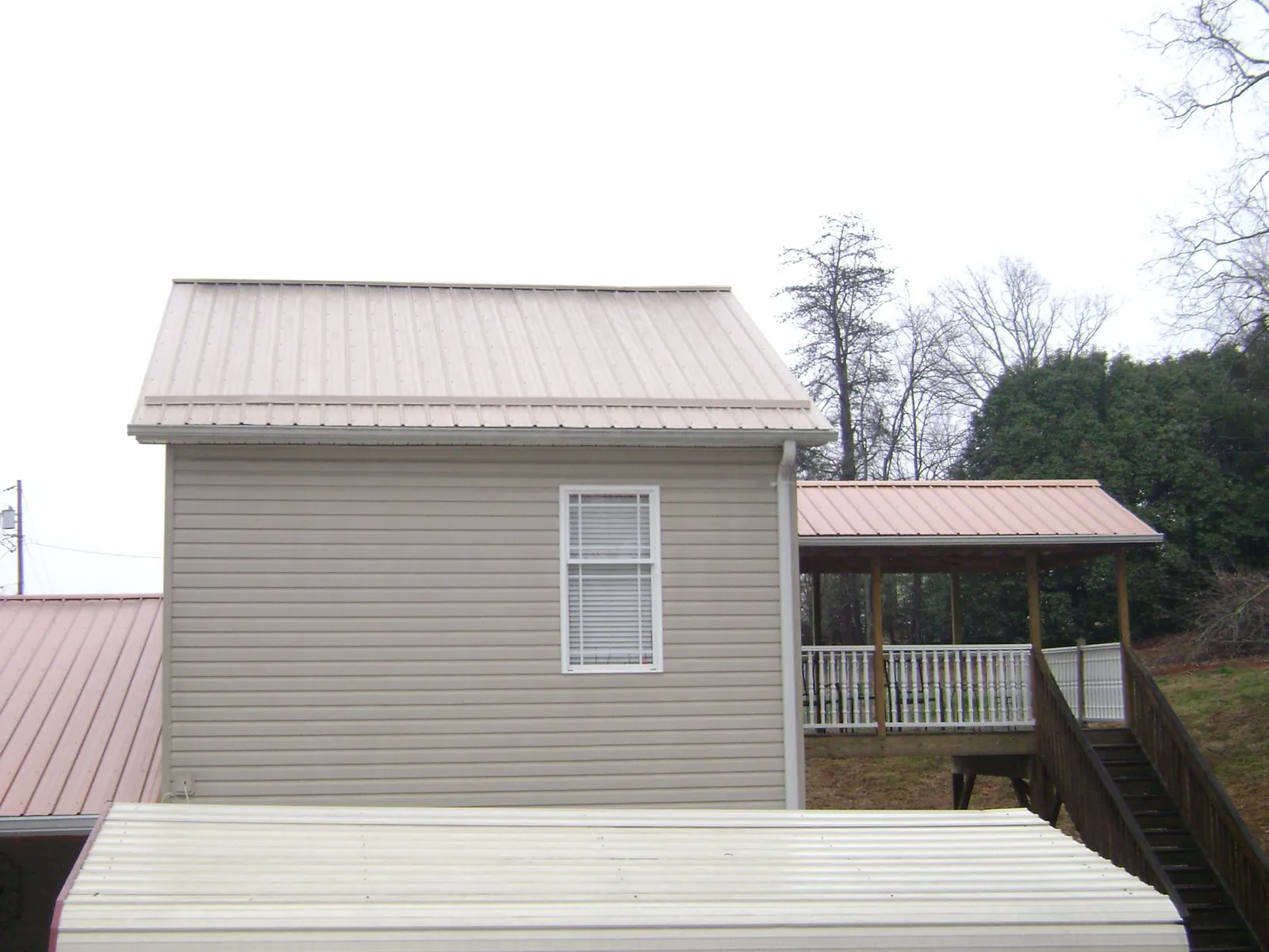 Tan metal roofs on a two story addition and attached porch, from a Roof Replacement job in Lenox