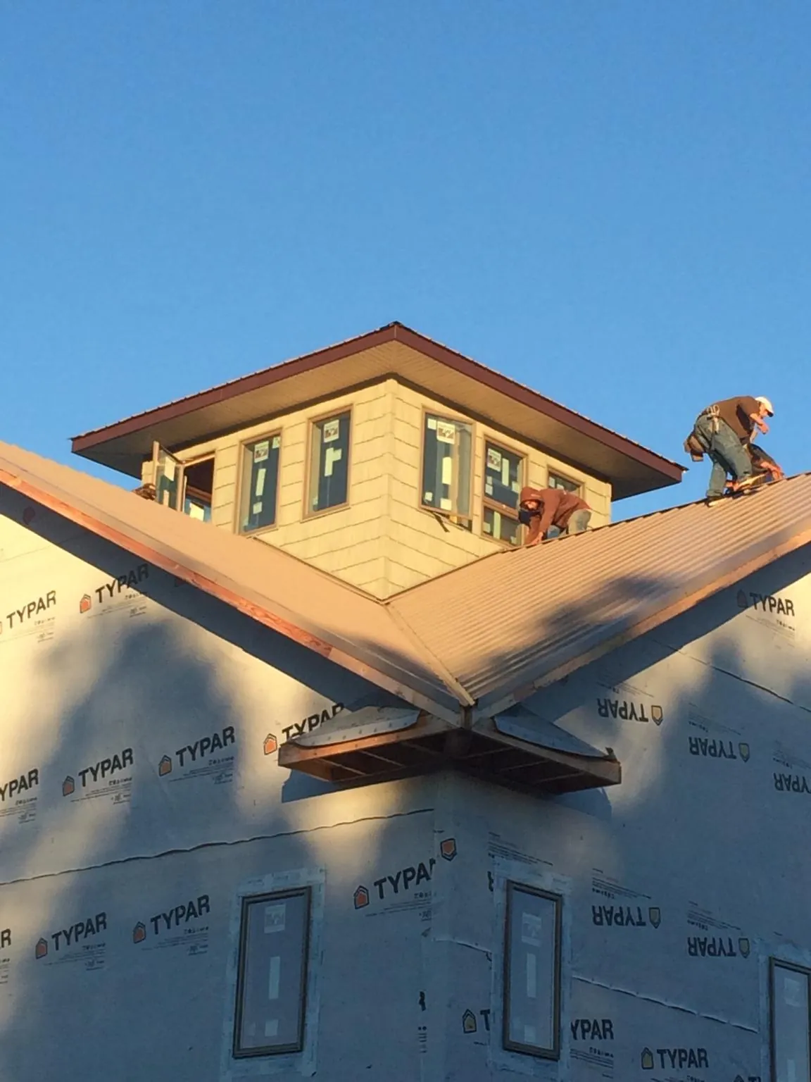 Roofers working around a rooftop cupola on a new metal roof at sunset — Roof Waterproofing in Lenox by Roofing Brothers